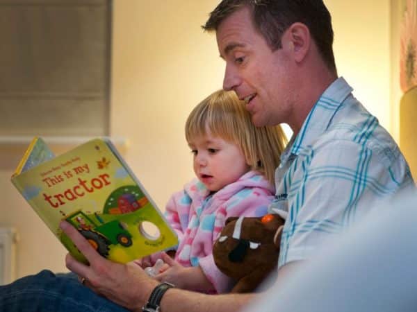 father reading to his daughter on holiday in Cornwall